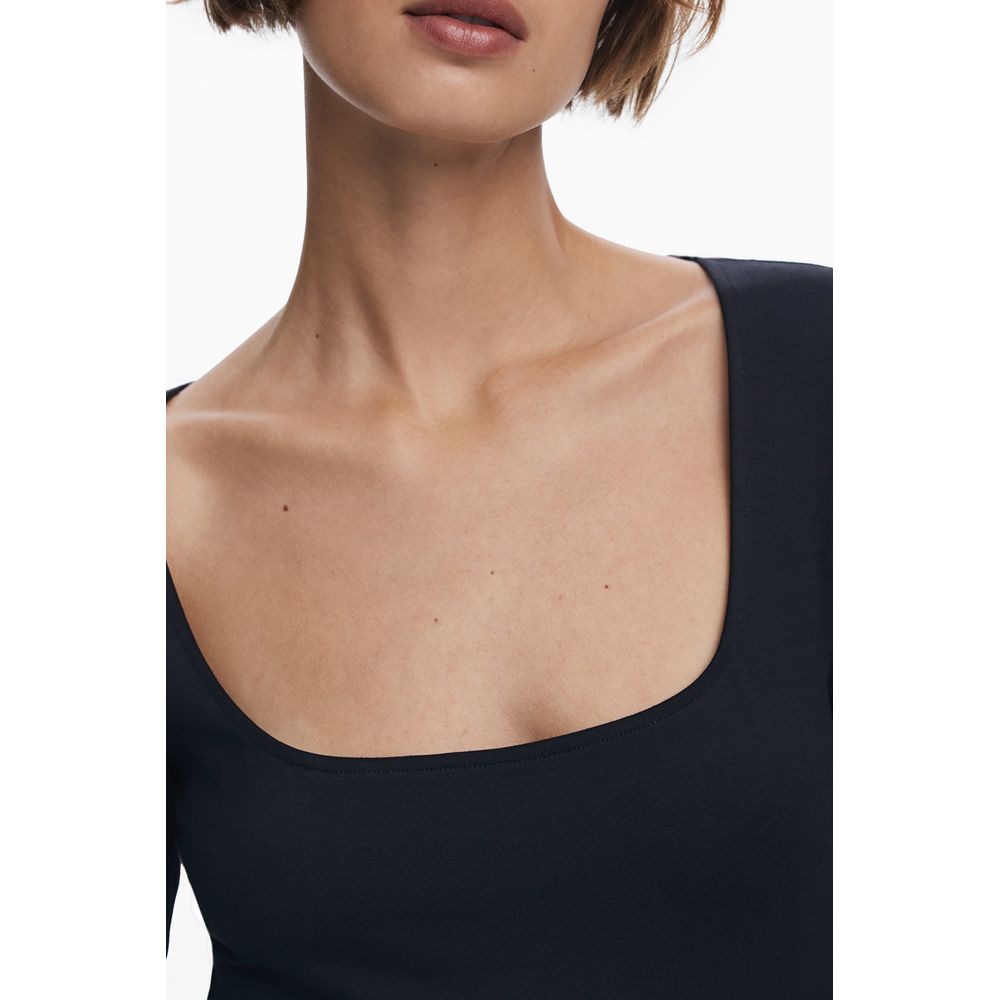 Black sleeveless top worn by a model on a white background