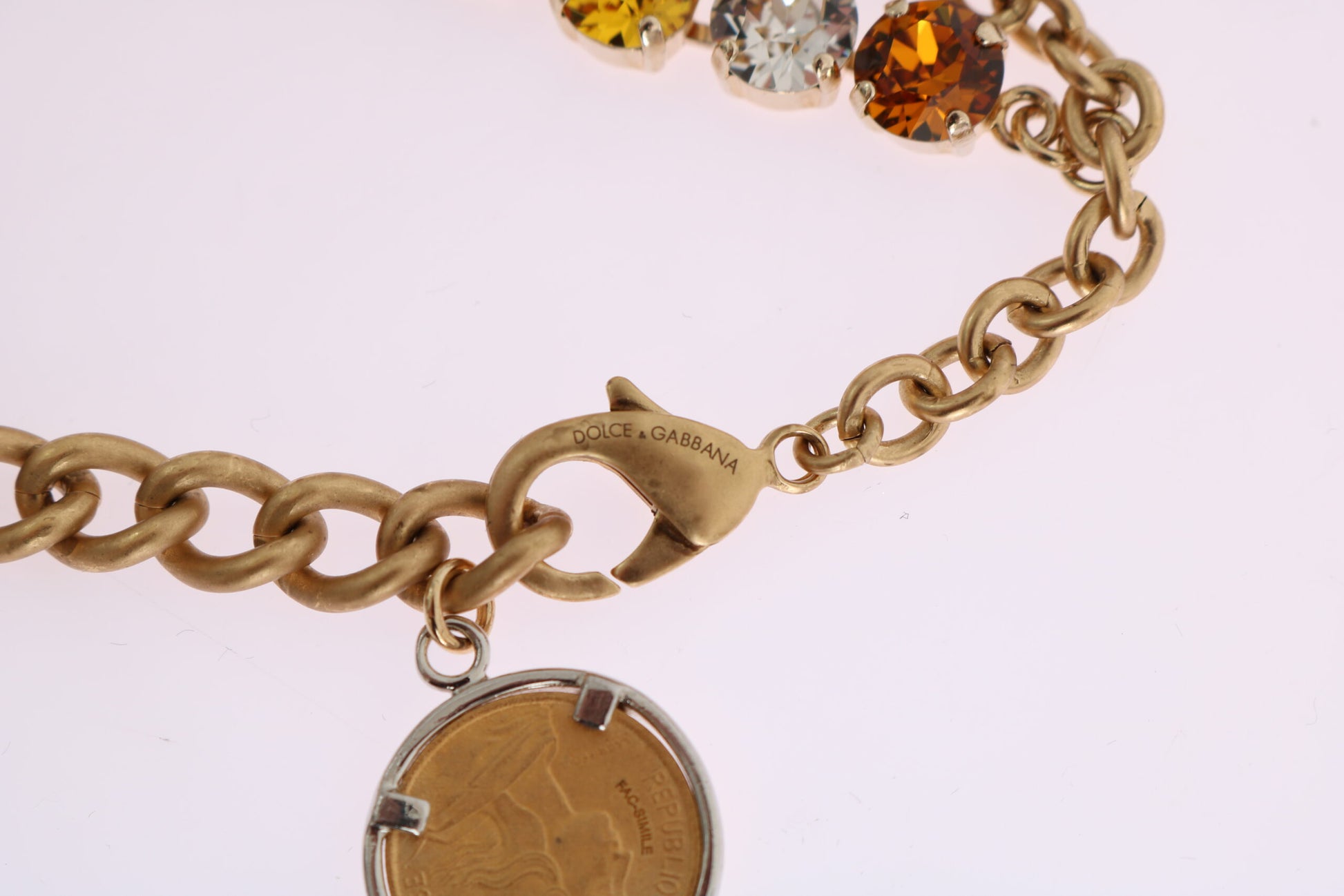 Gold chain bracelet with a clasp and coin charm on a white background